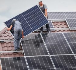 Men,workers,mounting,photovoltaic,solar,moduls,on,roof,of,house.