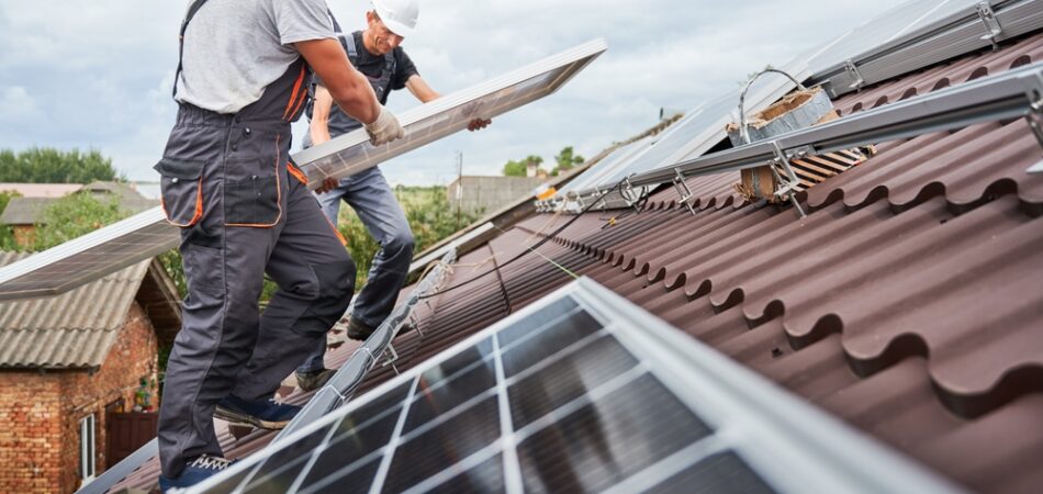 Men,technicians,carrying,photovoltaic,solar,moduls,on,roof,of,house.